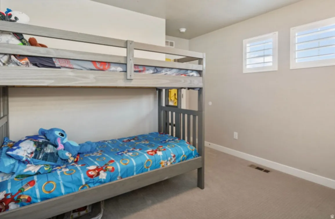 Carpeted room featuring two windows with white louvered blinds and neutral-toned walls