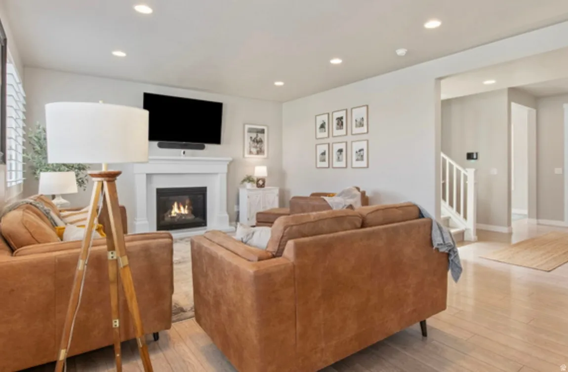 Living area featuring a gas fireplace with a white mantel, recessed lighting, and light wood-finish flooring