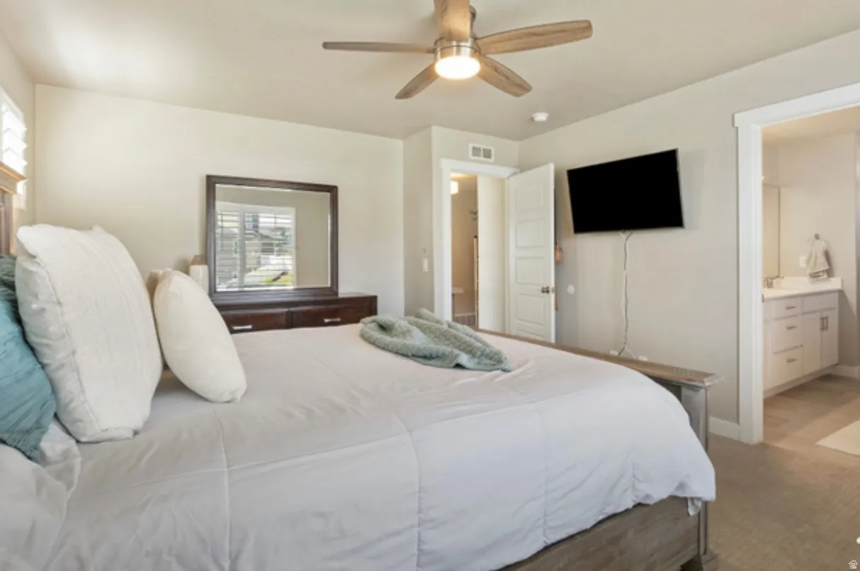 Carpeted bedroom featuring a ceiling fan, window with white plantation shutters, and a white six-panel door