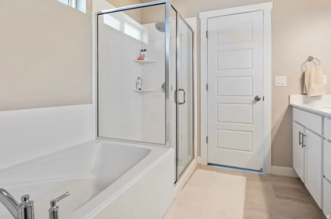 Modern bathroom featuring a built-in tub, a glass-enclosed shower, a vanity with a white countertop and base cabinetry, and light-colored flooring