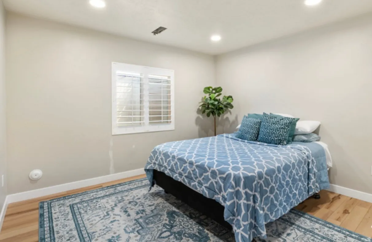 Room featuring light-toned walls, recessed ceiling lighting, and wood-finish flooring