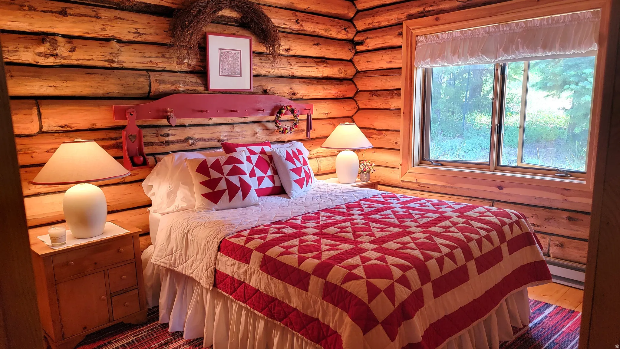 The  charming primary bedroom has pine plank flooring, and a custom area rug covering the floor.
