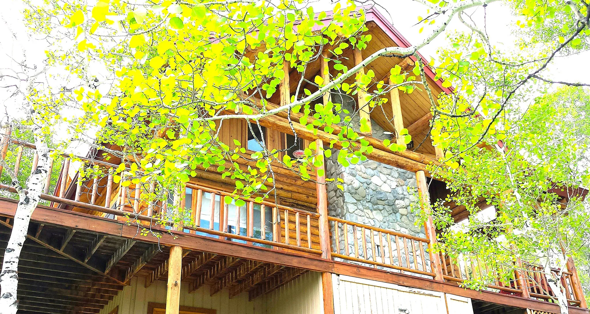 The covered deck on the south side of the cabin. There is a place for a hot tub by the window, and a storage shed is located below the deck.