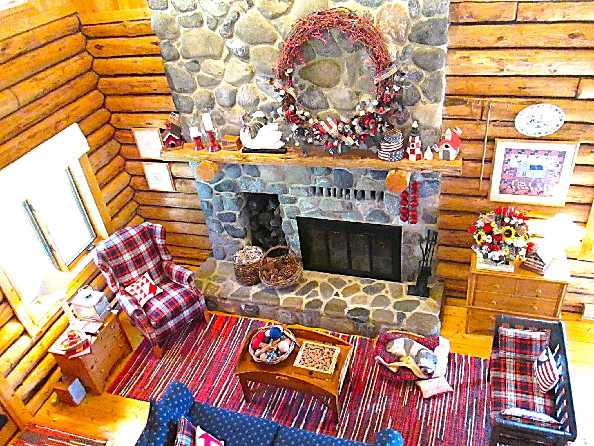 A two-story fireplace made of gray river rock from American Fork Canyon, has a log niche, a raised hearth, and a log mantle. There is an electric blower to warm the main floor.