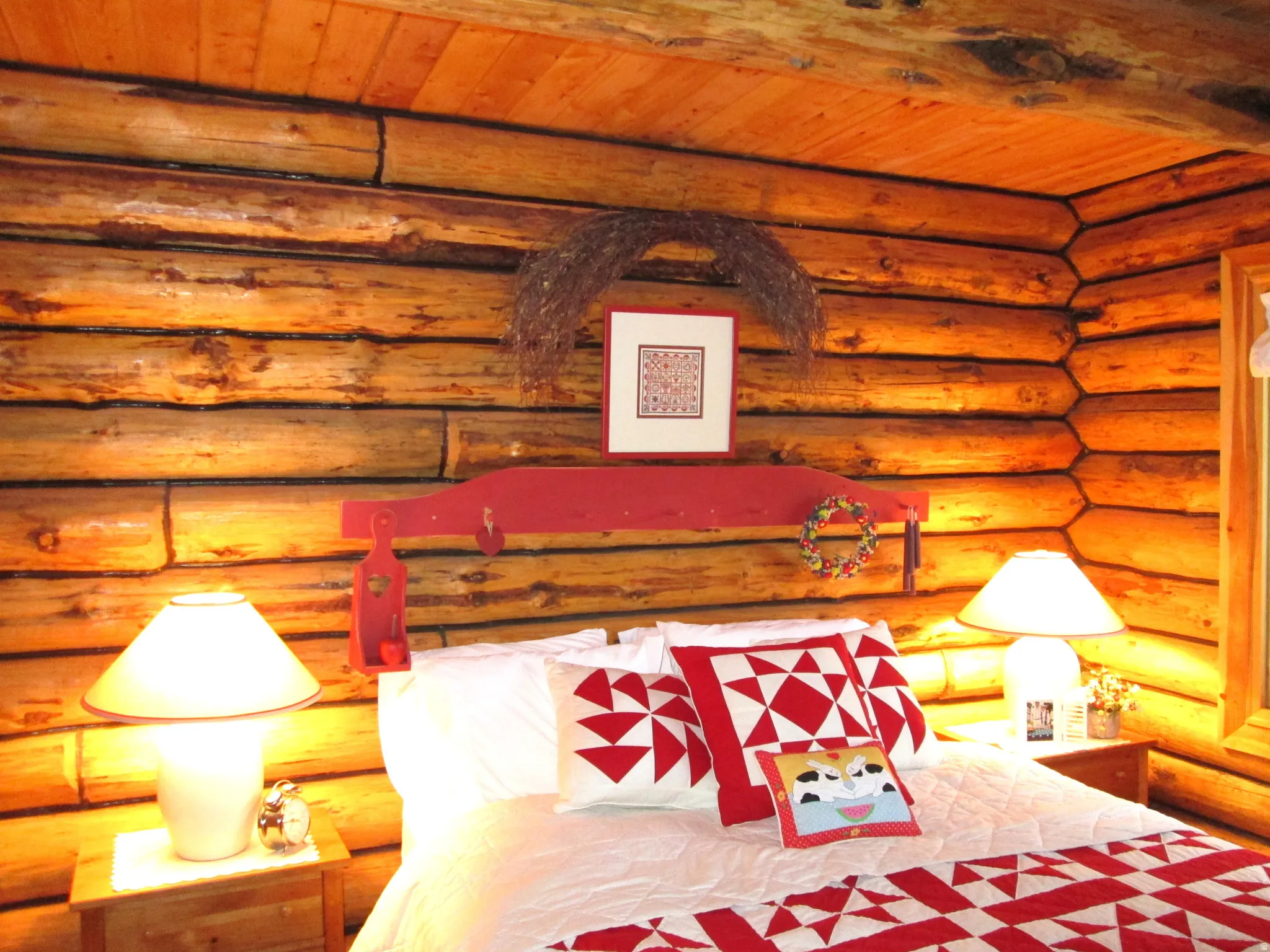 A queen bed, red headboard & two night stands are on the north wall.