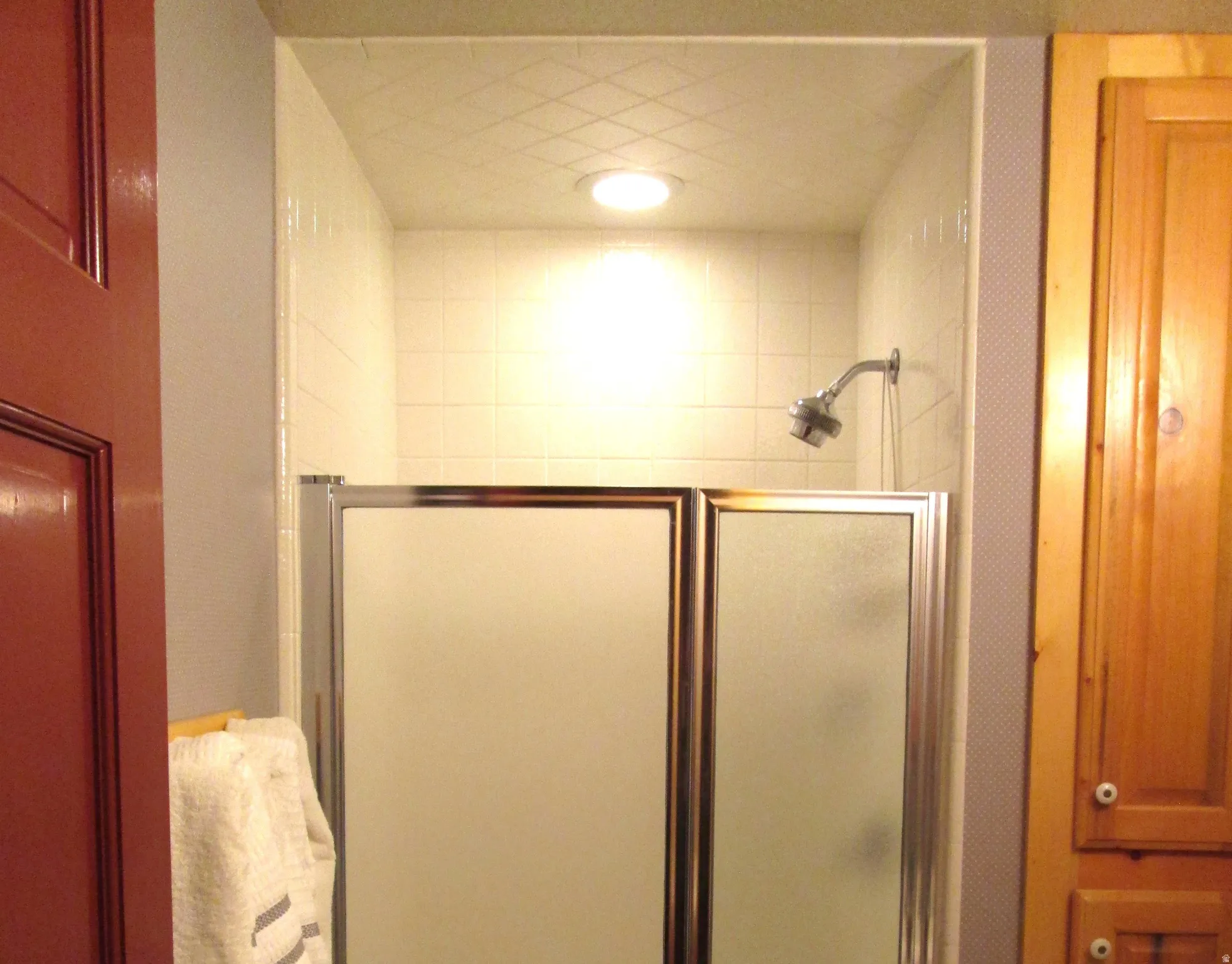 The shower has ceramic tile that covers the ceiling.