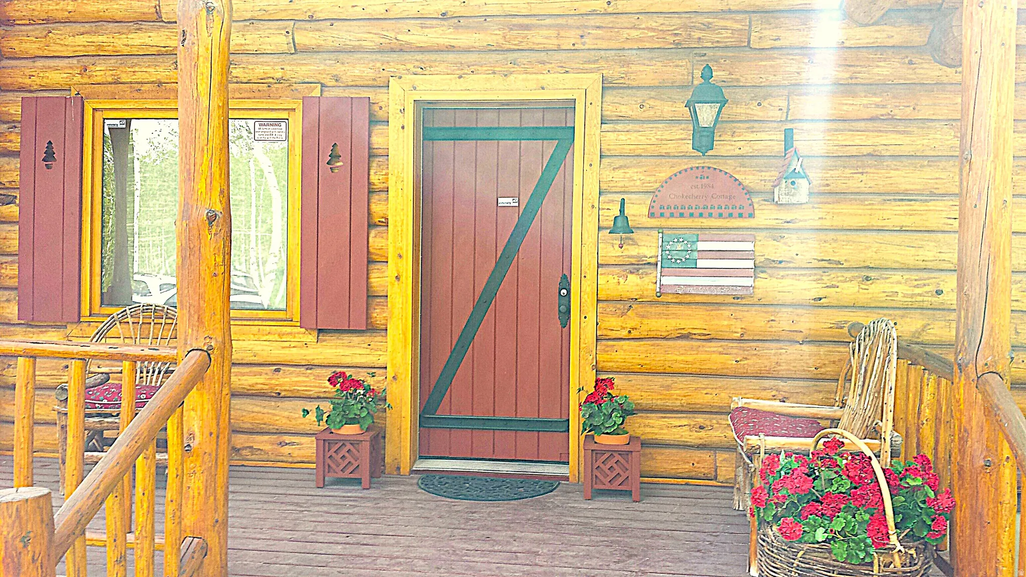 Front door and covered porch. The covered 2 story deck extends to the east and south side of the cabin.