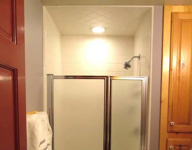 The shower has ceramic tile that covers the ceiling.