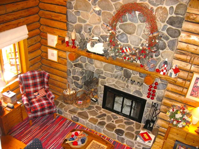 A two-story fireplace made of gray river rock from American Fork Canyon, has a log niche, a raised hearth, and a log mantle. There is an electric blower to warm the main floor.