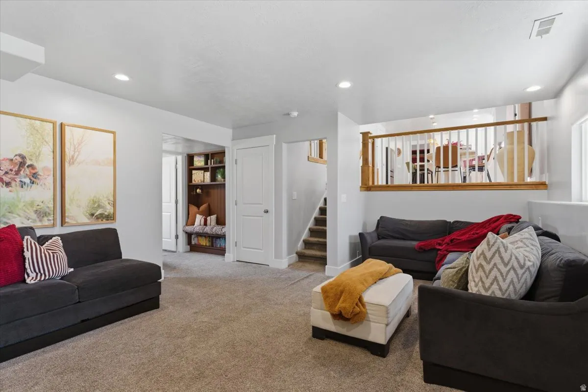 Spacious living area featuring neutral carpeting and recessed lighting