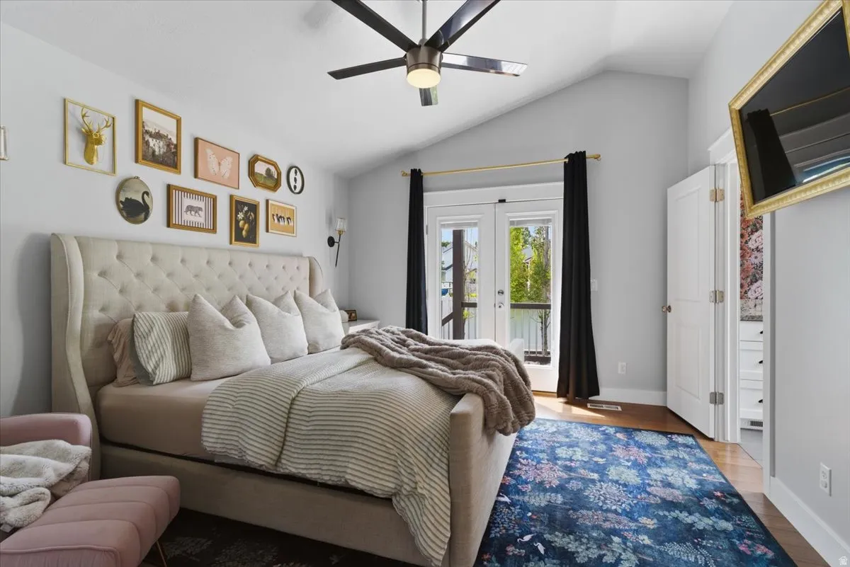 Vaulted ceiling room with hardwood-finish flooring, a ceiling fan, and French doors leading out to a private deck