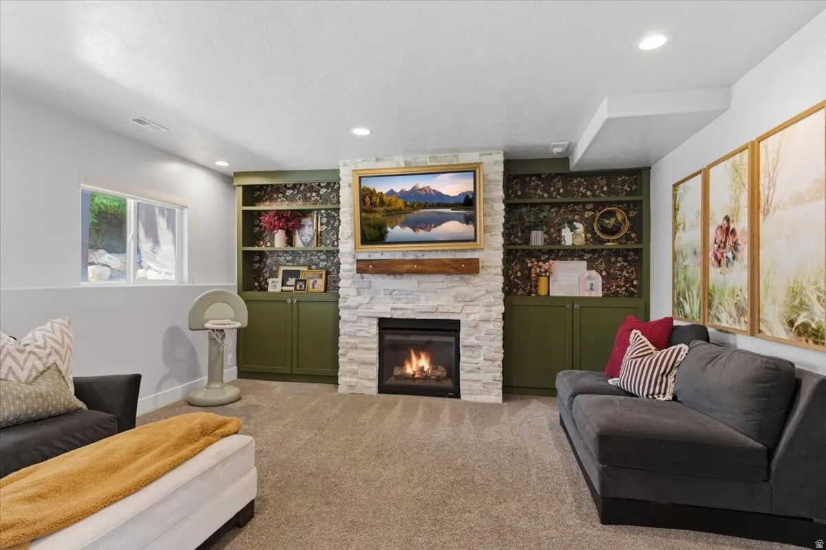 Stone-clad fireplace with a wood mantle and built-in shelving with cabinetry