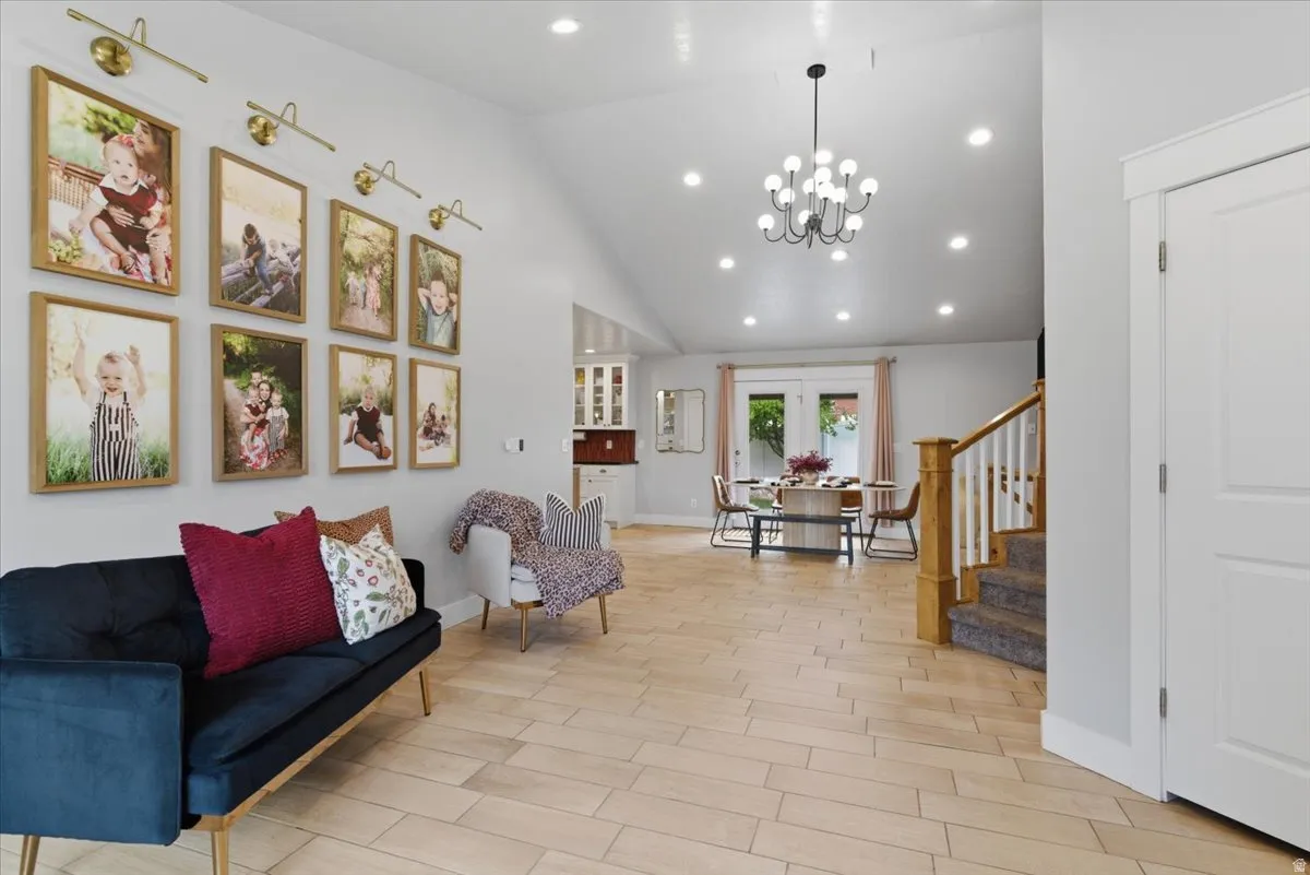 Open-concept living space featuring tile flooring, a vaulted ceiling with recessed lighting, and a contemporary chandelier