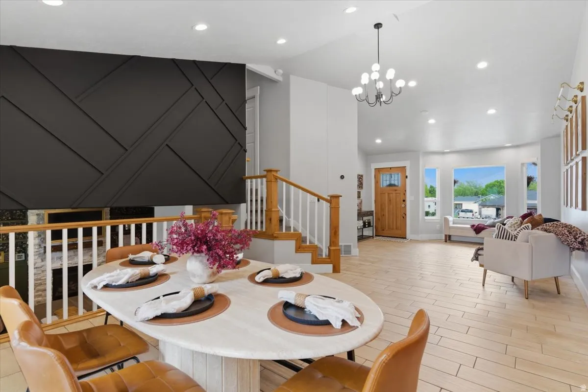 Open concept living area featuring a decorative dark accent wall, light tile flooring, and a natural wood entry door with glass inserts