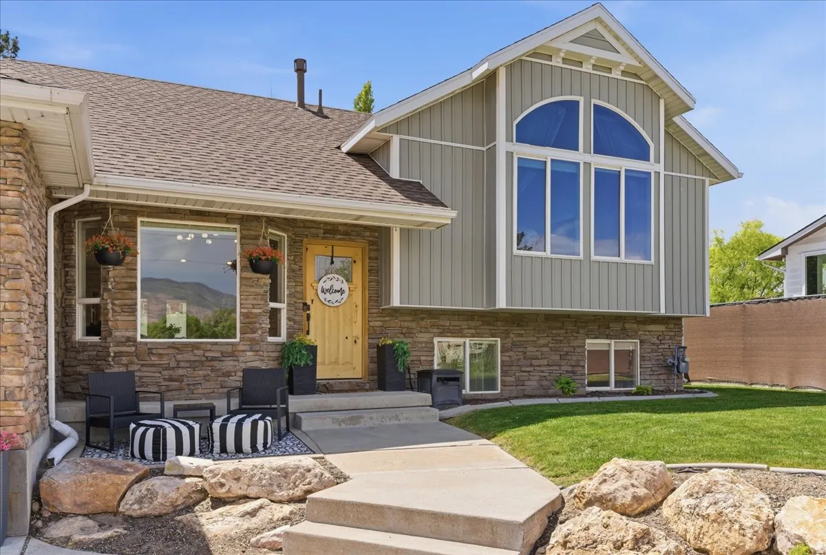 Stone facade with vertical siding accents, featuring a prominent arched window and a natural wood-finish entry door