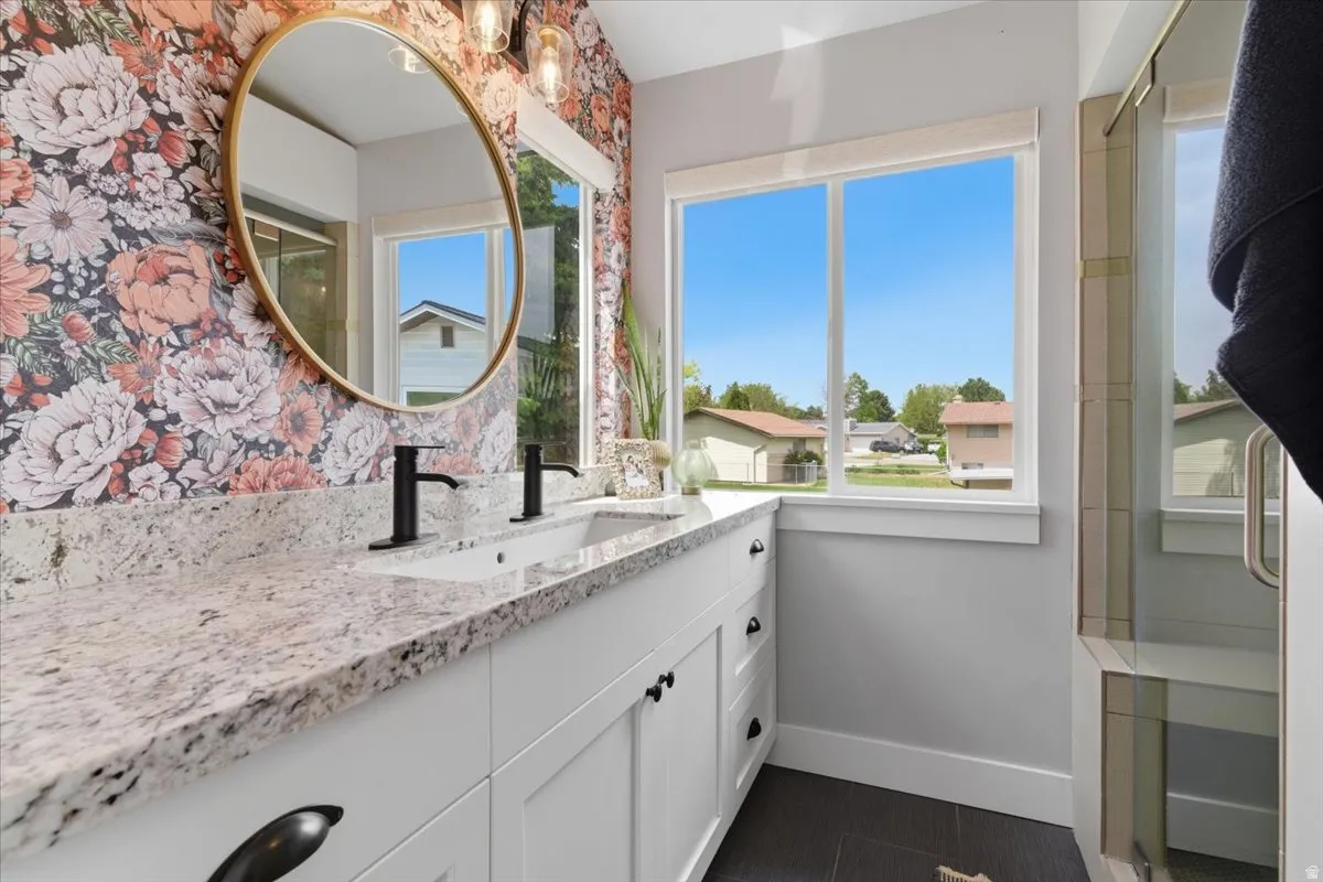 Dual vanity with white cabinetry, granite countertop, matte black fixtures, walk-in shower with dual shower heads