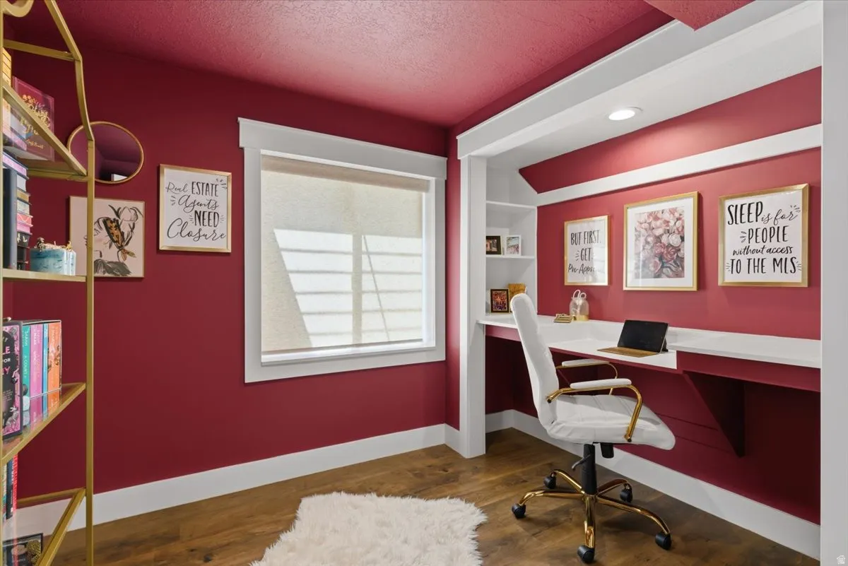Dedicated workspace featuring built-in shelving, integrated desk, recessed lighting and wood-finish flooring