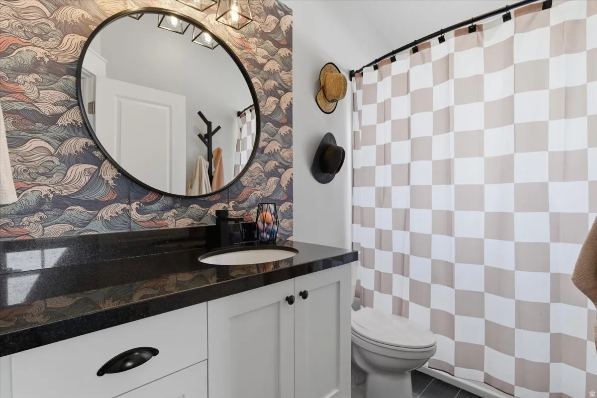 Bathroom featuring a white vanity with black hardware and a black granite countertop