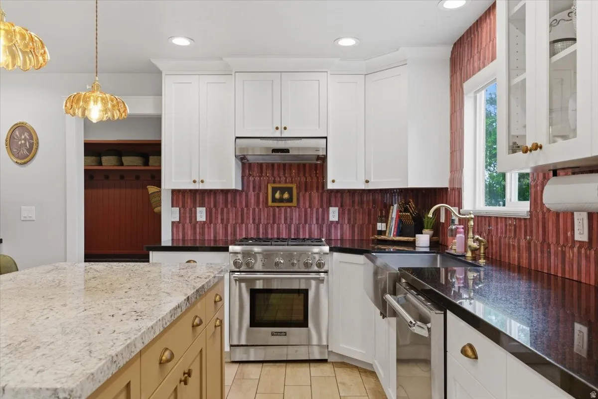 Kitchen featuring white cabinetry, stainless steel appliances, a large farmhouse sink and  granite countertops