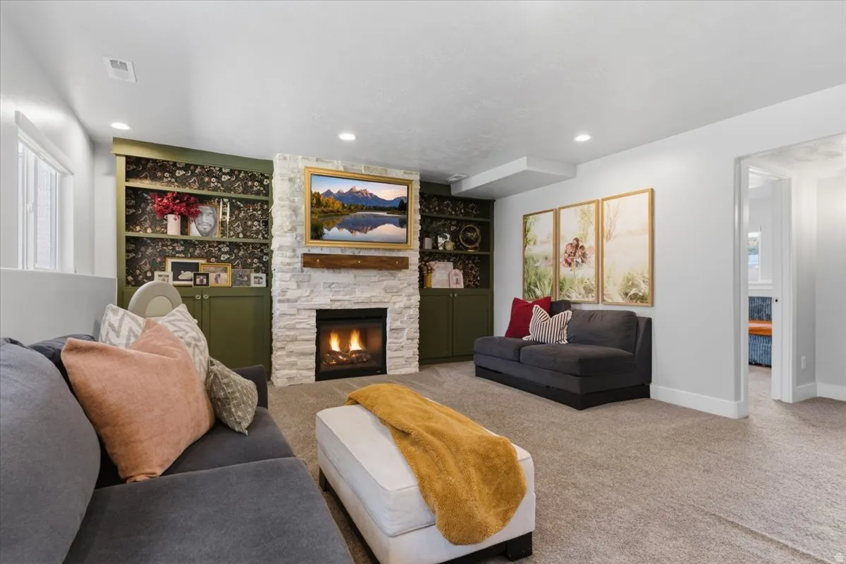 Stone-clad fireplace with a wood mantle, flanked by built-in shelving and cabinetry