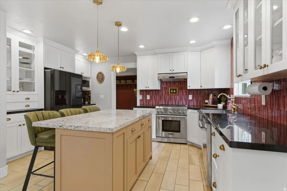Spacious kitchen featuring a large island with a two-toned countertop, white cabinetry, steel appliances, and tile flooring