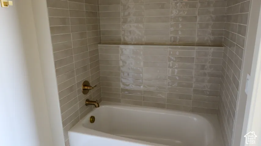 Spa-inspired bathroom featuring subway tile surround, a soaking tub with brushed brass fixtures, and a chrome towel bar for convenient storage and organization