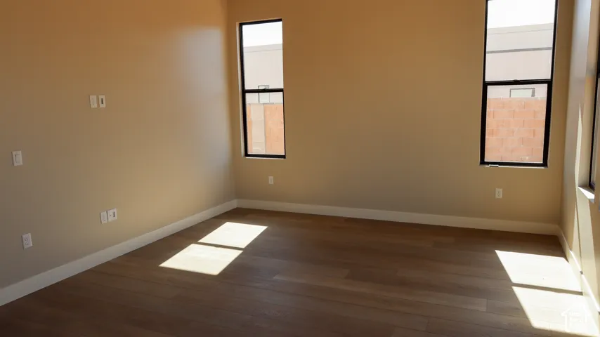Wood-finish flooring, neutral wall tones, and tall windows with black frames