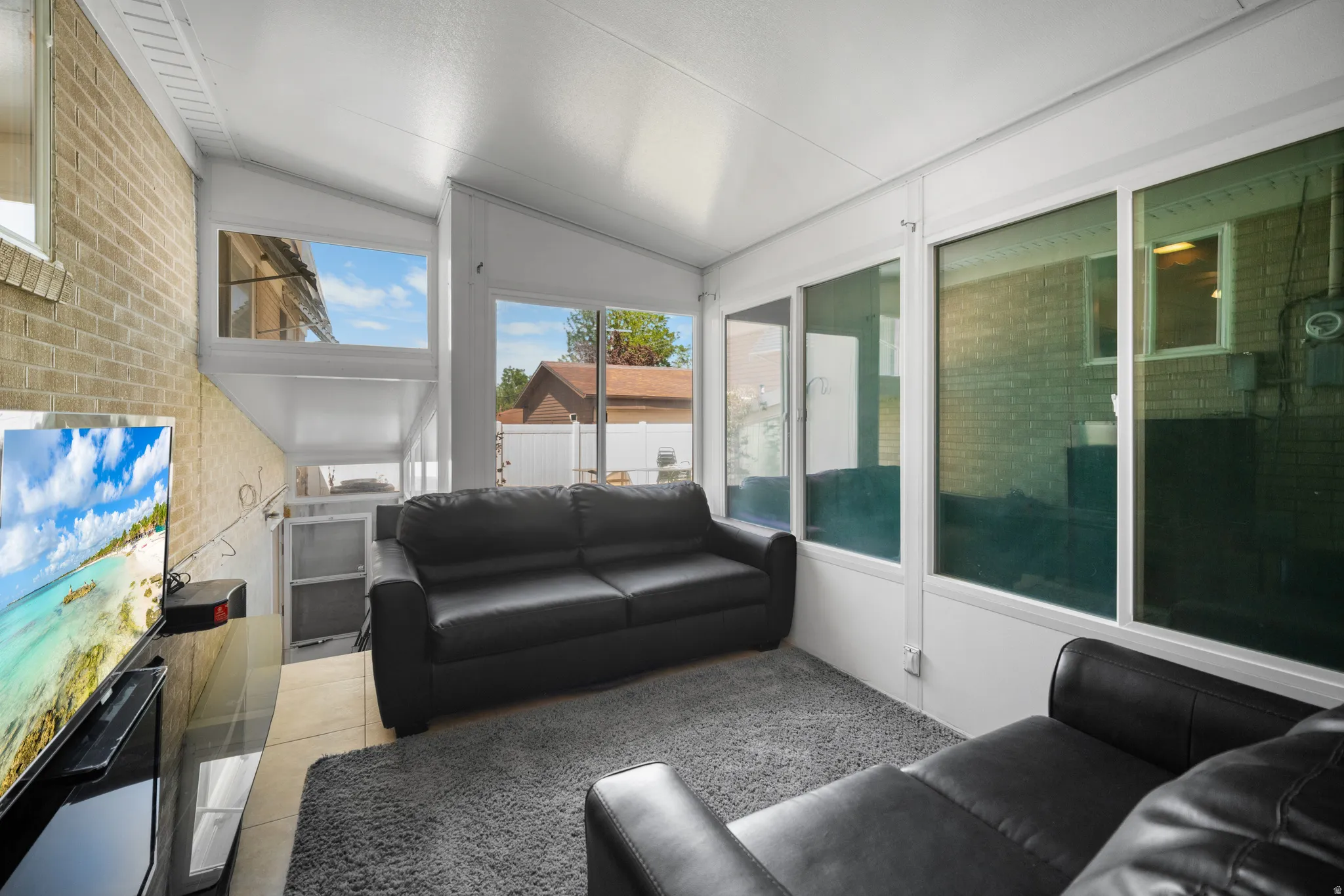 Sunroom featuring a vaulted ceiling and an exposed brick wall