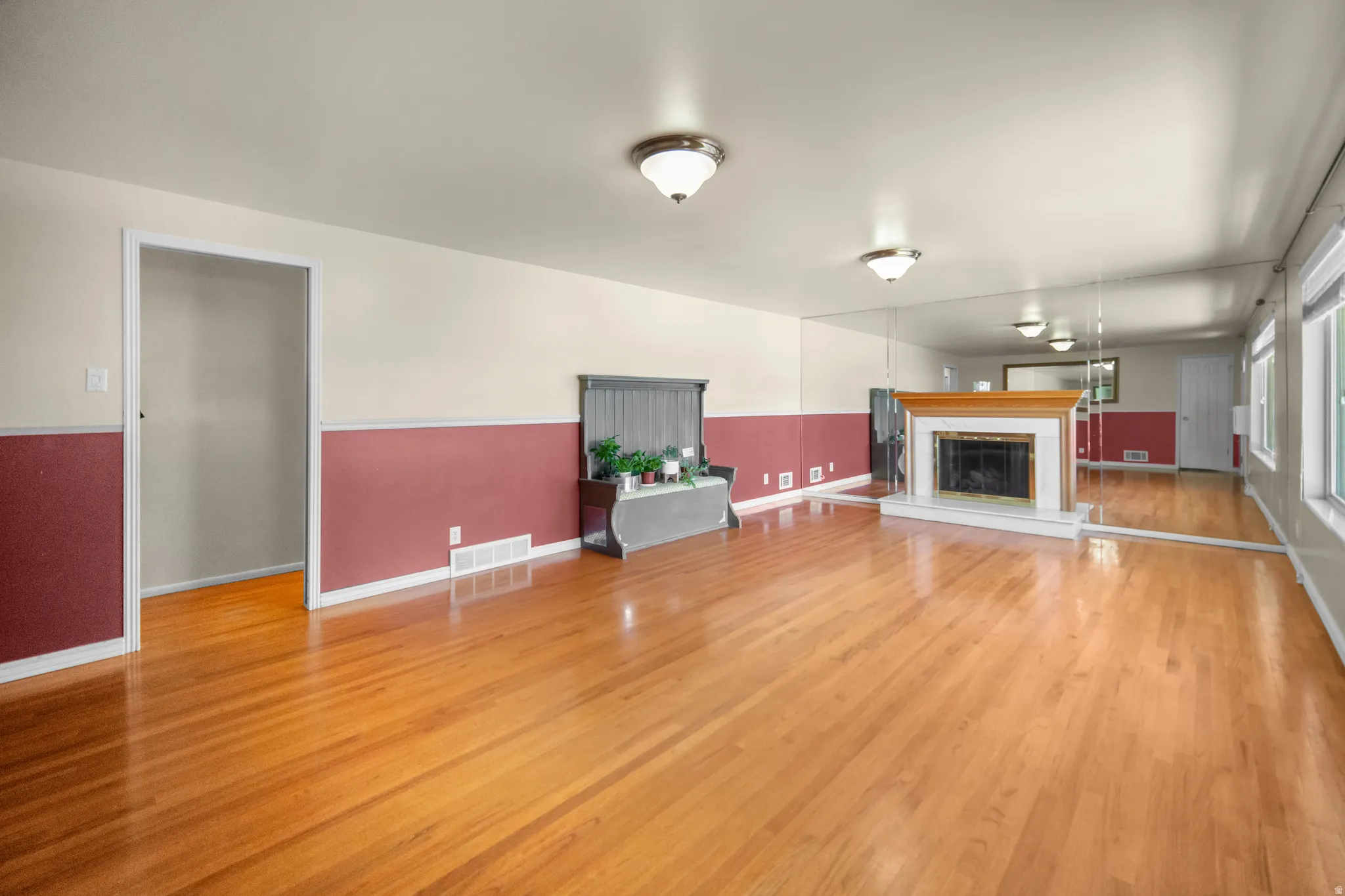 Hardwood flooring throughout featuring a fireplace with a wood mantle and hearth