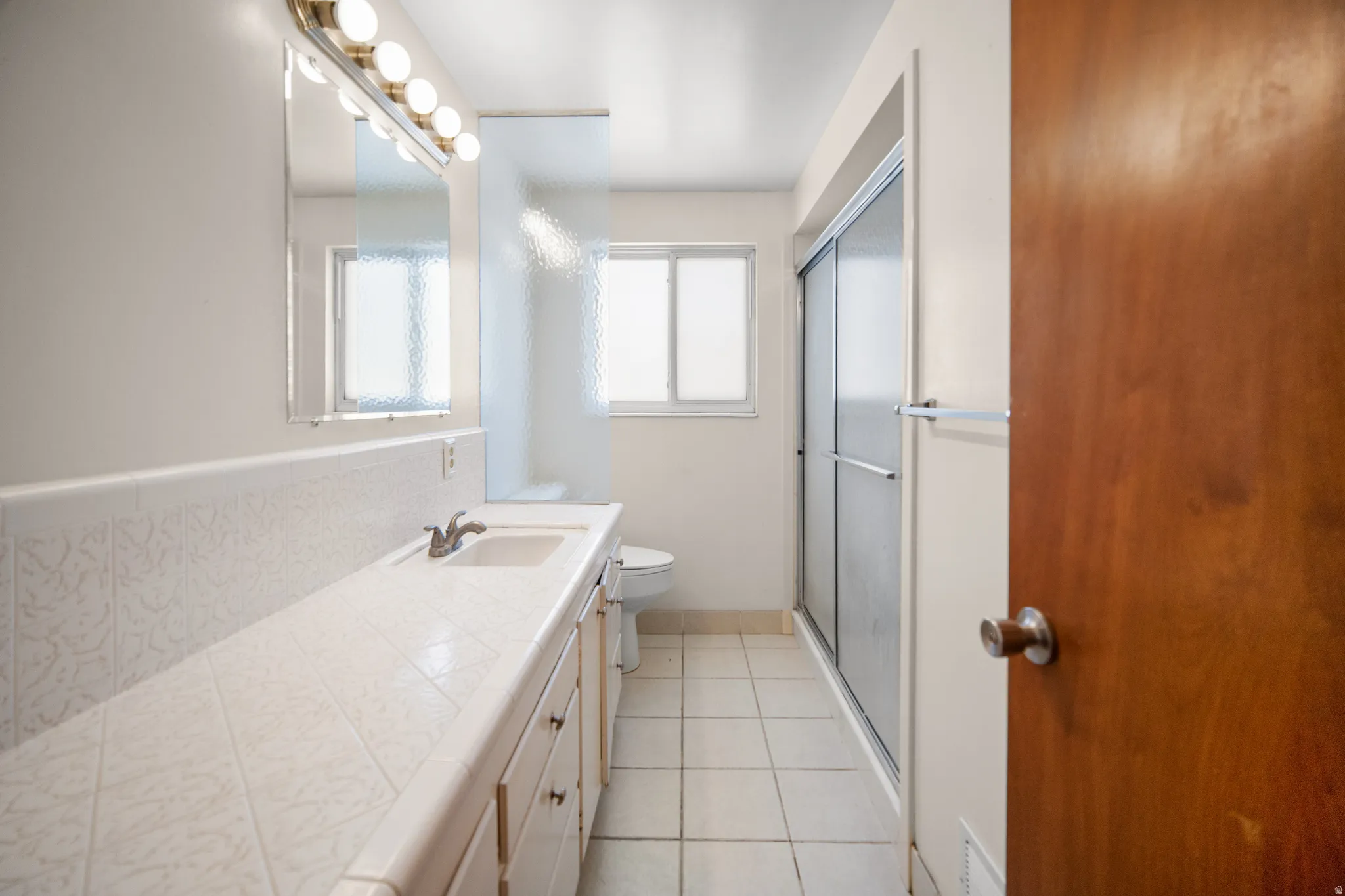 Bathroom vanity with integrated sink, patterned tile backsplash, and a large mirror