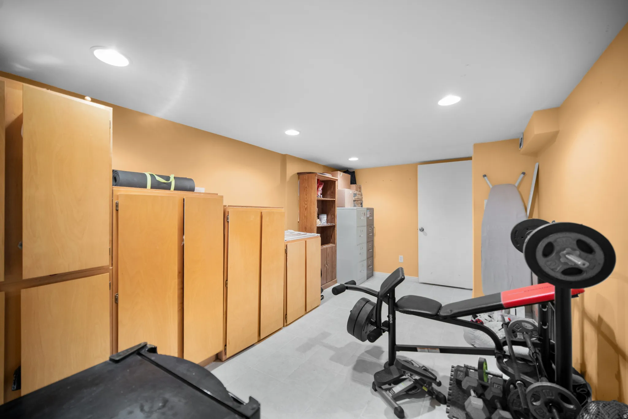 Spacious room featuring extensive built-in cabinetry, recessed lighting, and a white interior door