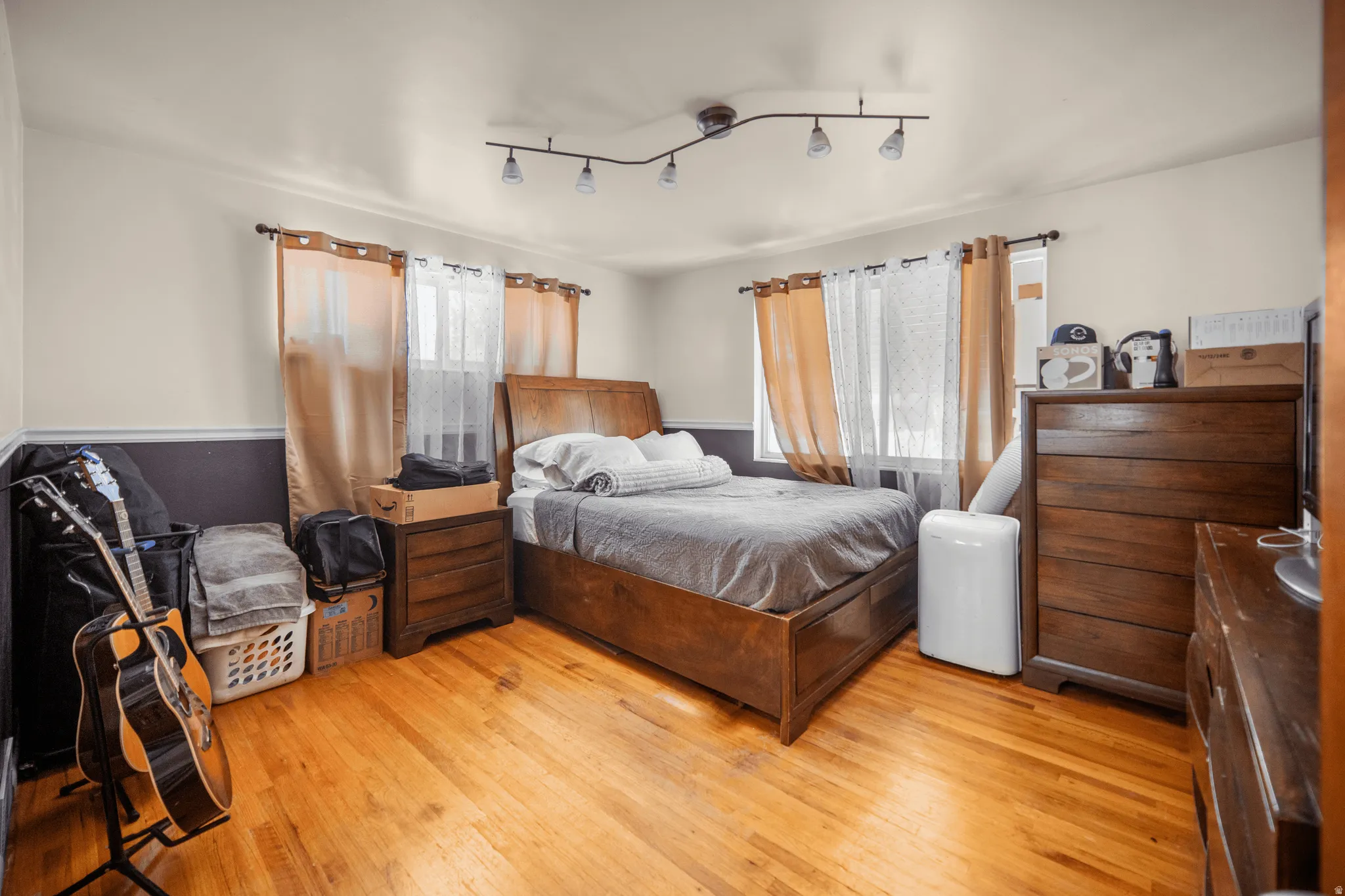 Bedroom featuring wood-finish flooring, track lighting, and a two-tone wall finish