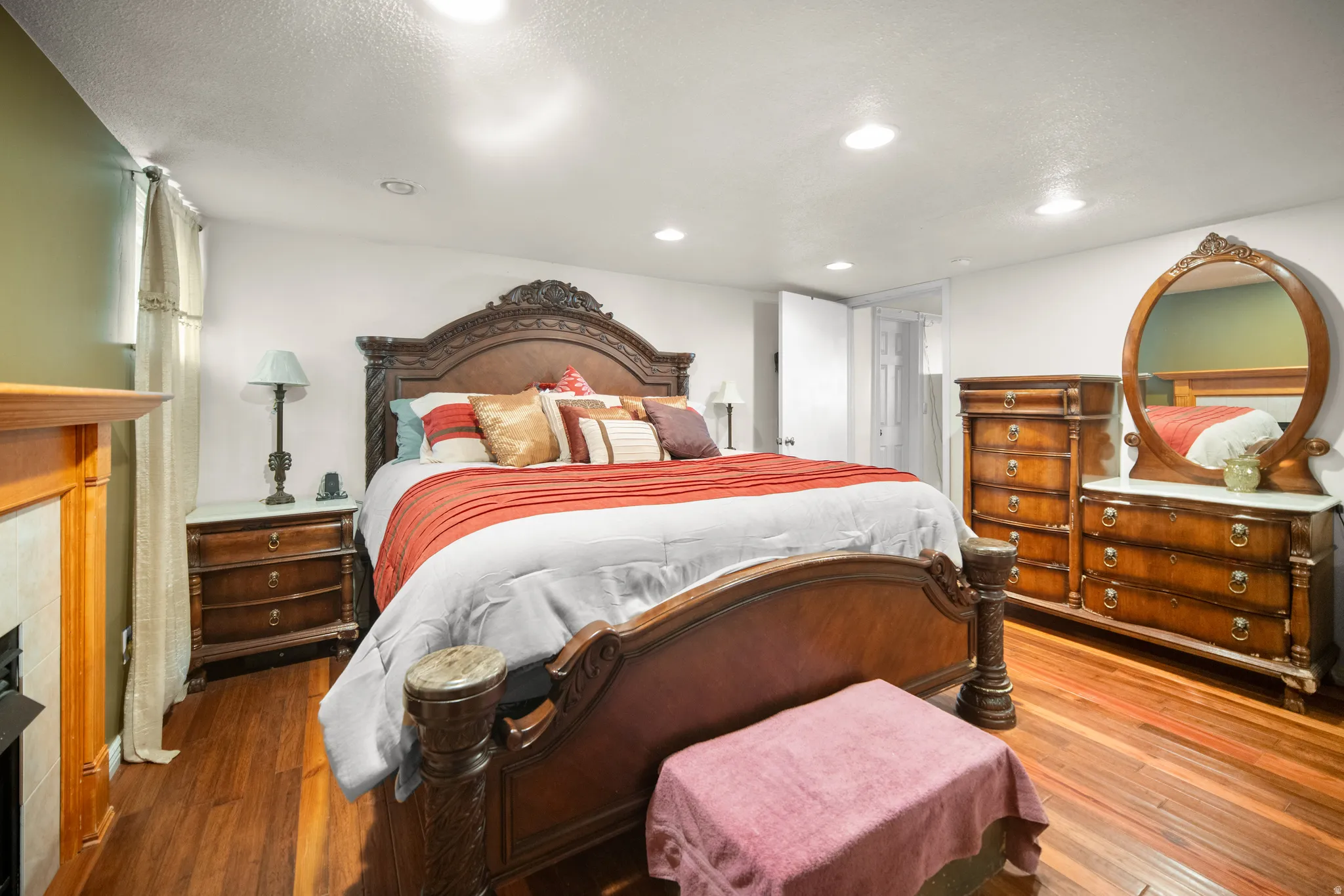Spacious room featuring wood-finish flooring, recessed lighting, a fireplace with a wood mantel, and white walls