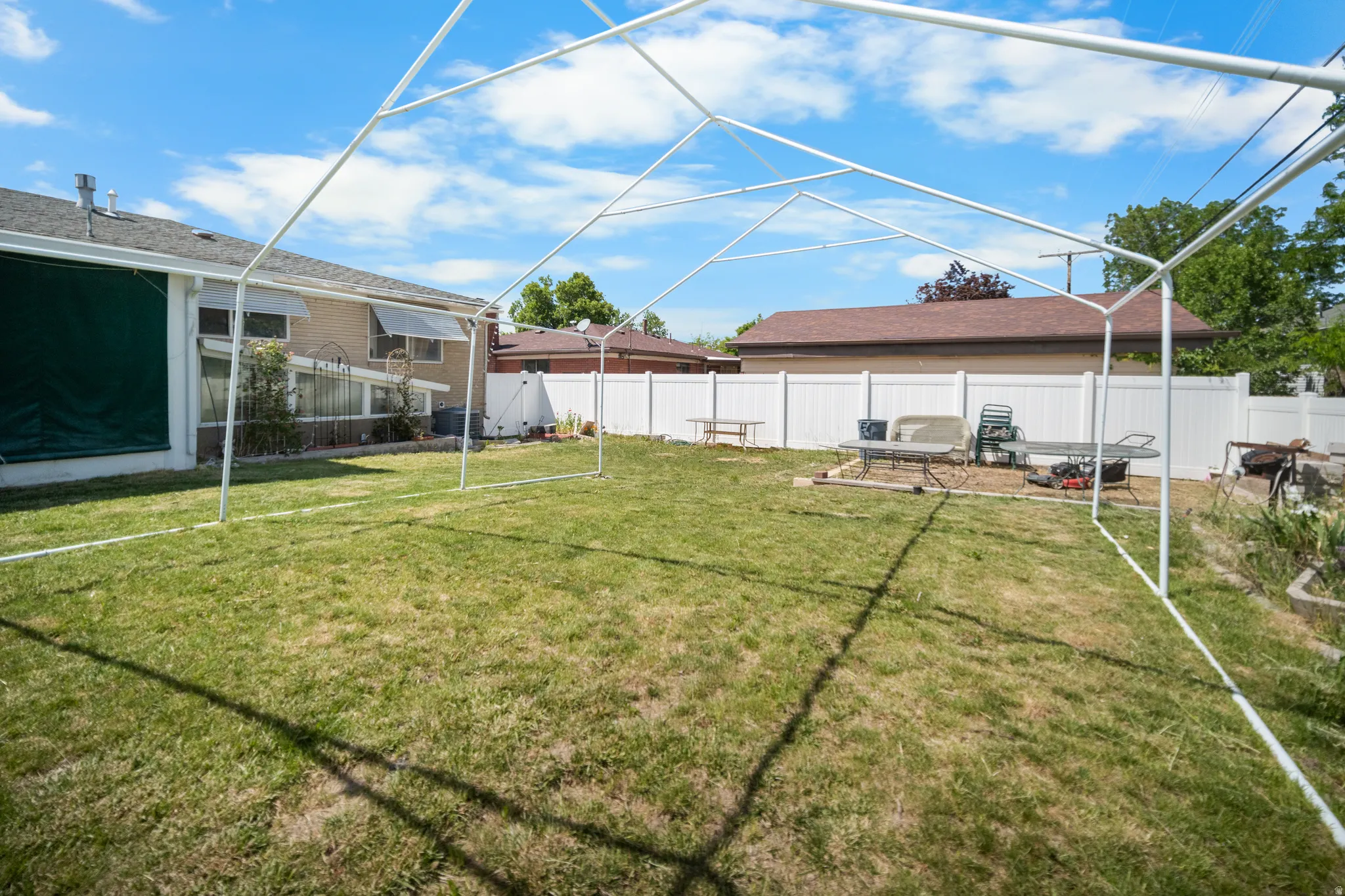 Expansive backyard featuring a green lawn and a white privacy fence
