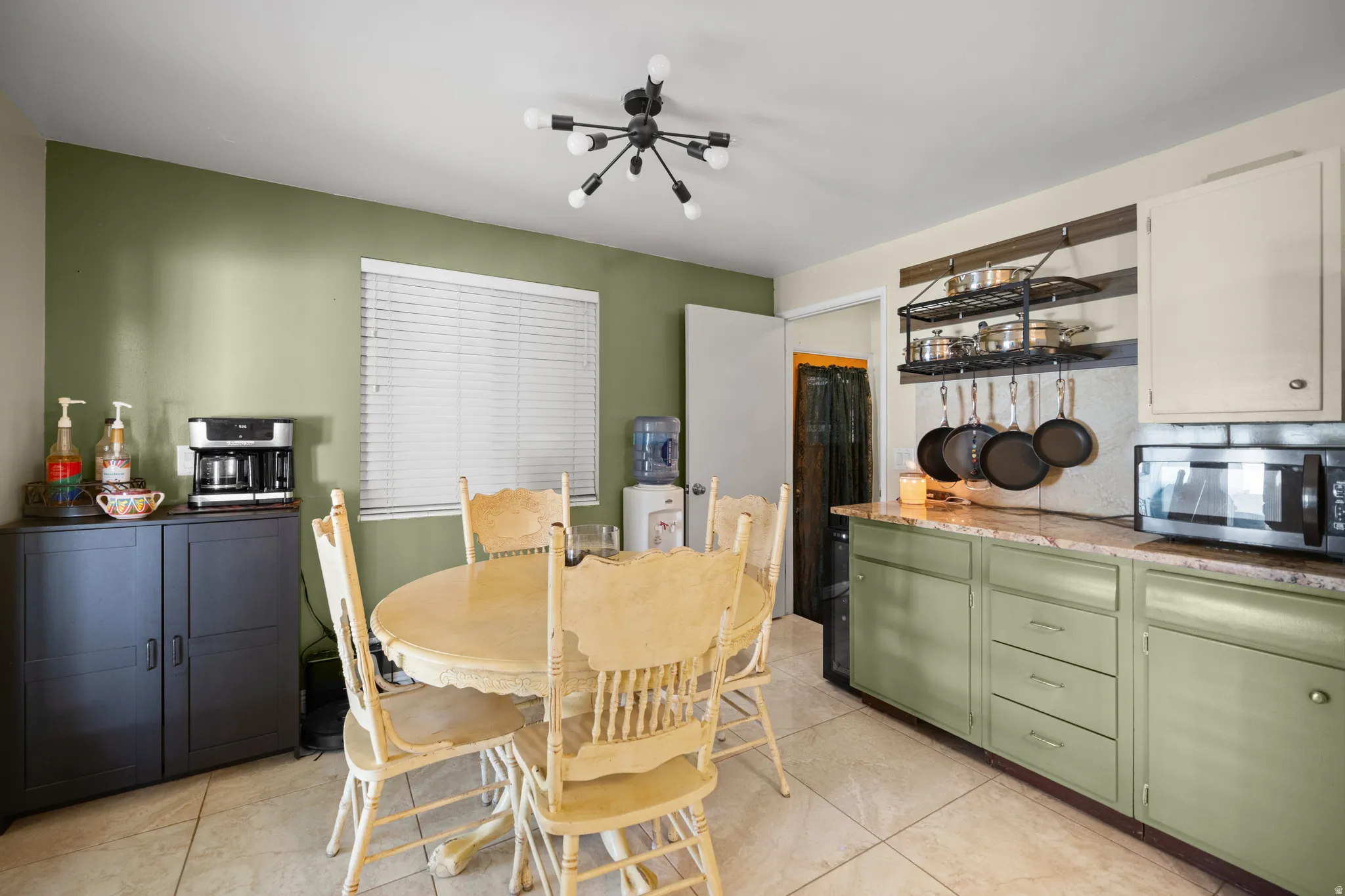 Kitchen space featuring green cabinetry, light-toned countertops, and tile flooring