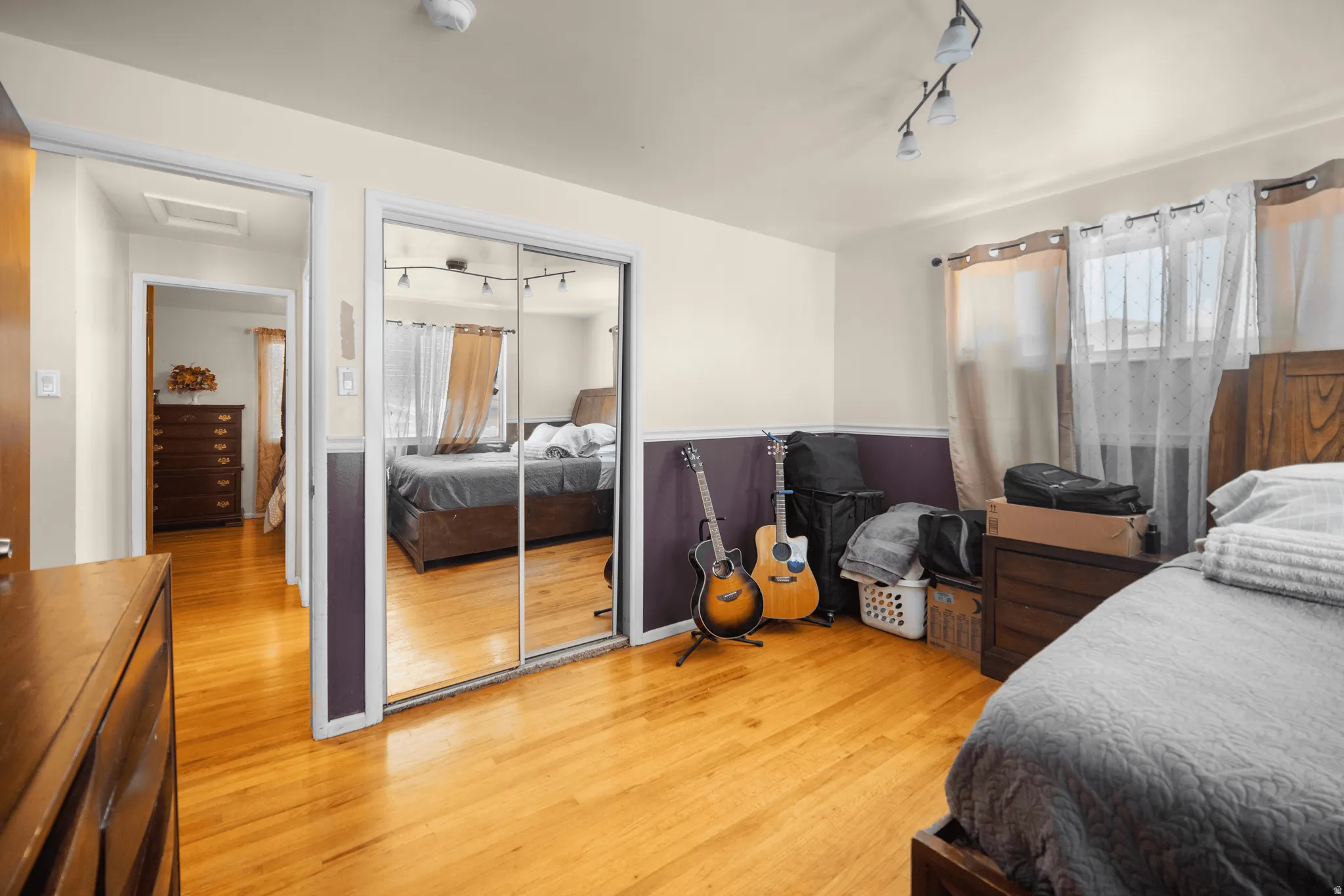 Hardwood flooring extends throughout this room, featuring a two-tone wall treatment and a multi-pane window