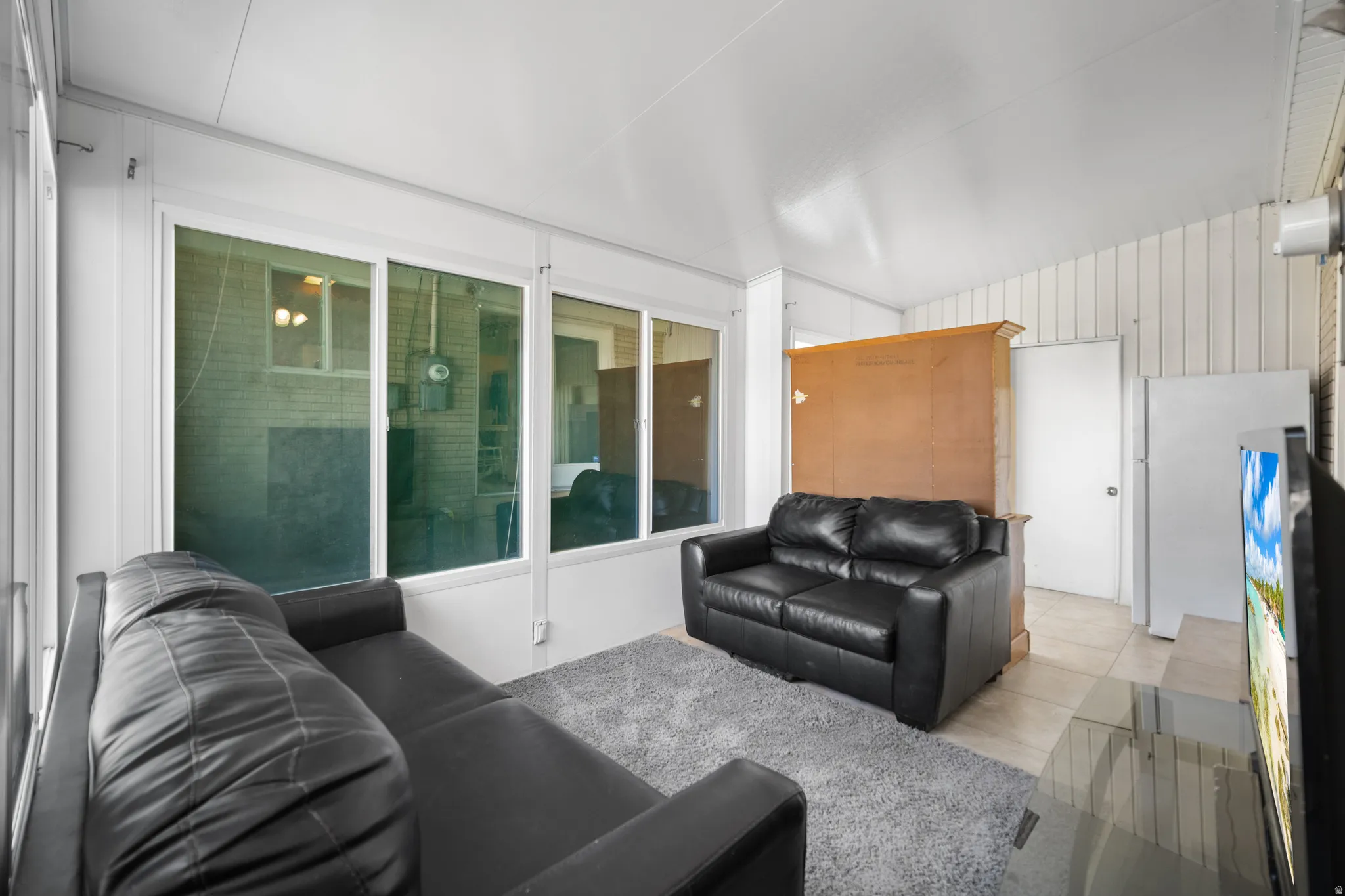 Room with white paneled walls and ceiling, featuring multiple large windows
