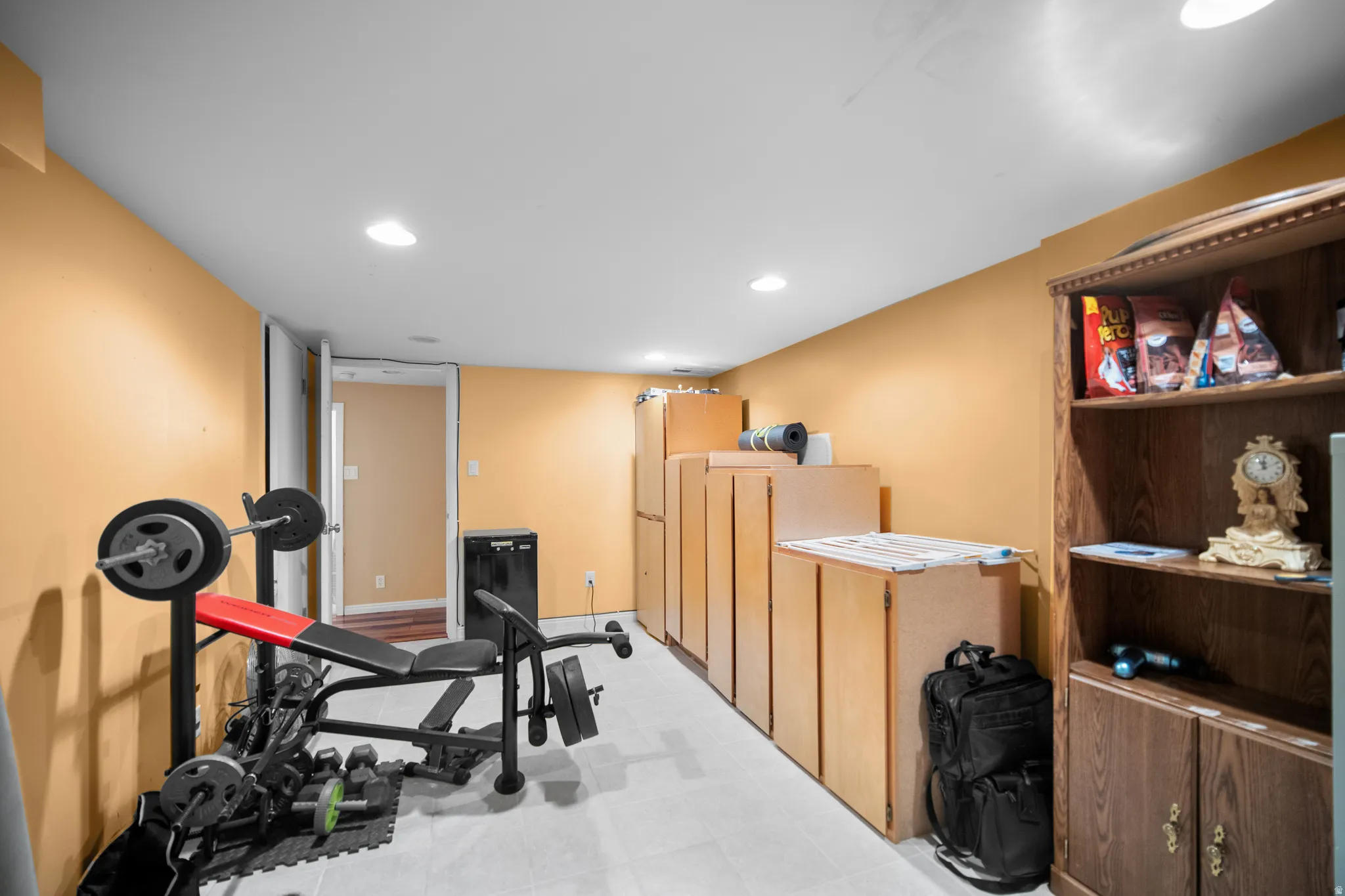 Versatile lower level space featuring recessed lighting, light-colored flooring, warm-toned walls, and a built-in storage system with multiple cabinets