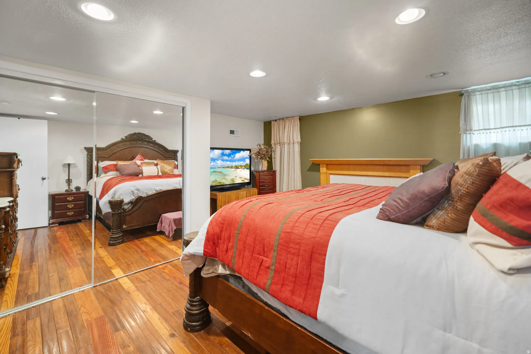 Bedroom featuring wood-finish flooring, recessed lighting, mirrored closet doors, and painted walls