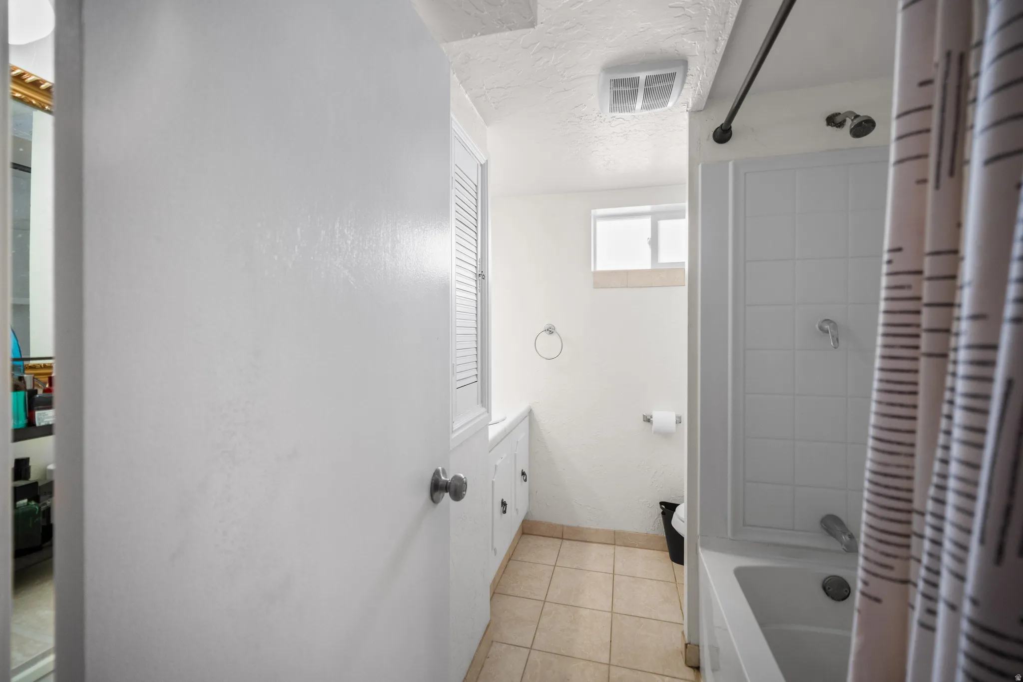 Bathroom featuring a white subway tile shower, white built-in cabinetry, and neutral floor tiling