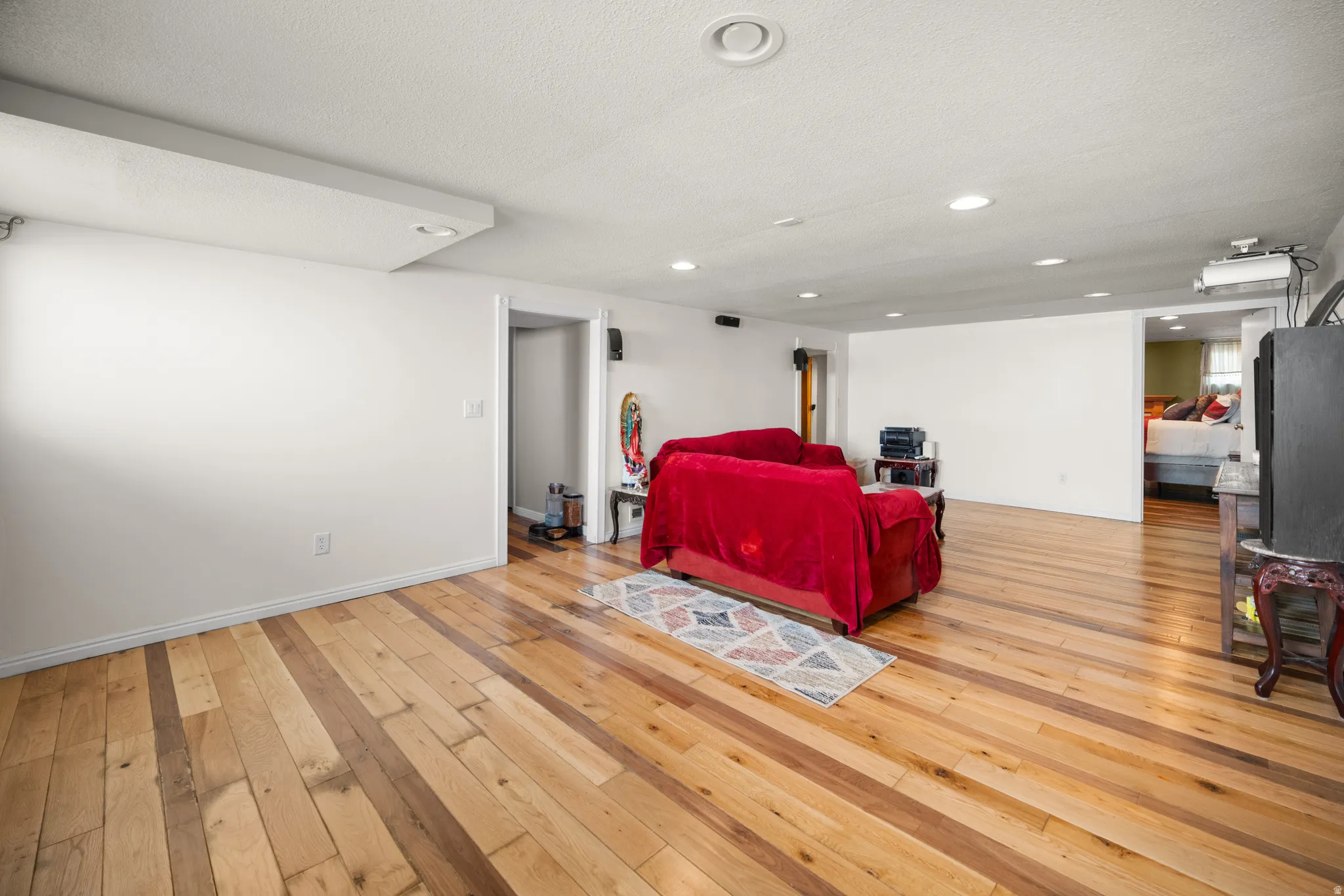 Spacious room featuring wood flooring, recessed lighting, and white walls