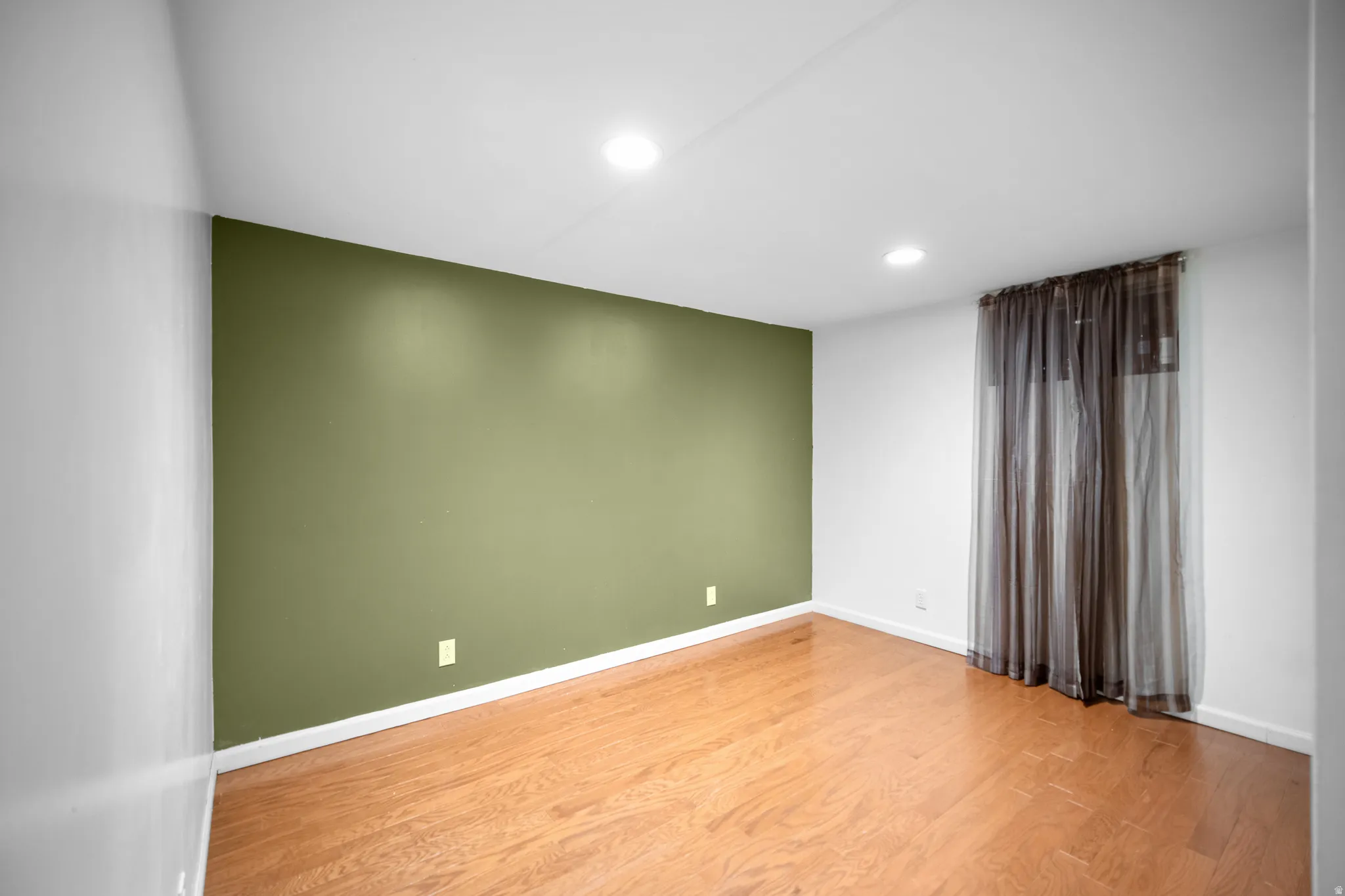 Room with wood-finish flooring, recessed lighting, and a window with sheer drapes