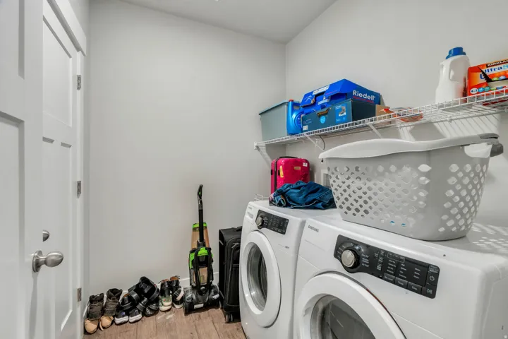 Dedicated laundry space featuring a white front-load washer and dryer set, wood-finish flooring, and a white interior door