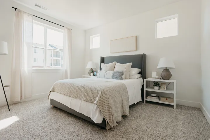 Carpeted room featuring multiple windows, a large window with sheer drapes, a smaller upper window, and white painted walls