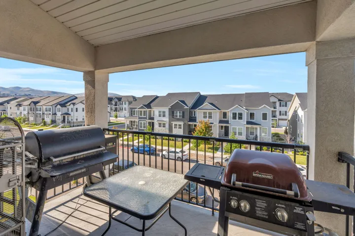 Covered balcony featuring a concrete floor, black metal railing, and neighborhood views