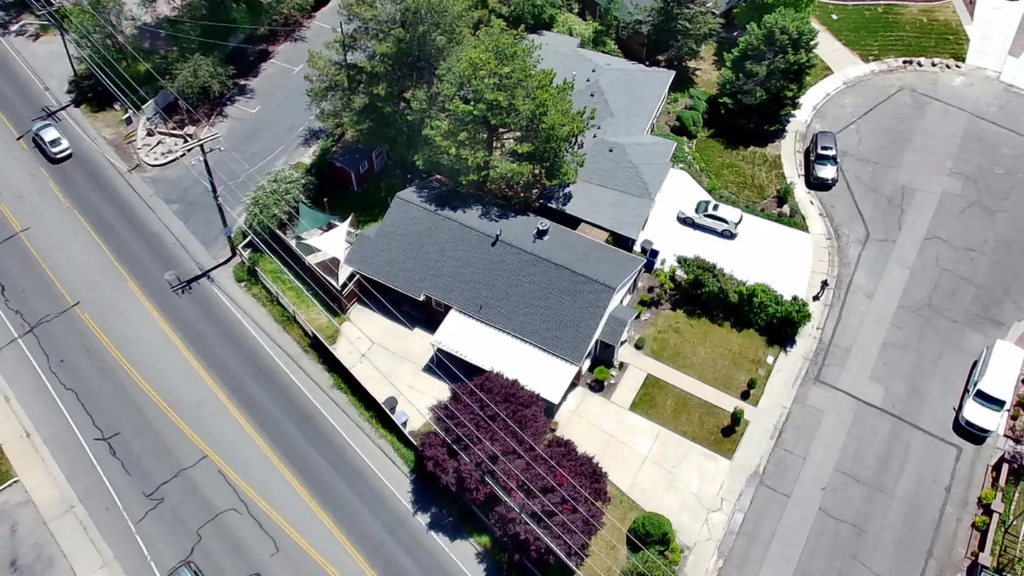 Property featuring a dark shingle roof, concrete driveway, and established landscaping