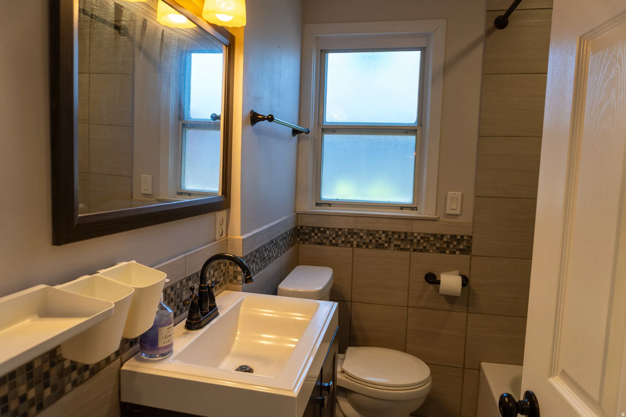 Contemporary bathroom featuring a vanity with an integrated sink, a dark framed mirror, and a wall-mounted light fixture