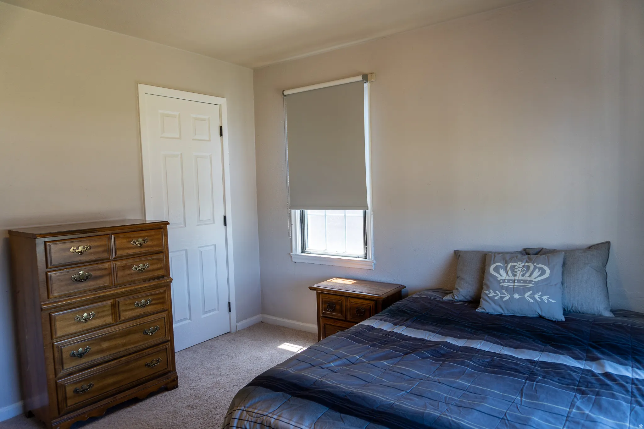Neutral-toned room featuring a white paneled door, light-colored walls, and carpet flooring