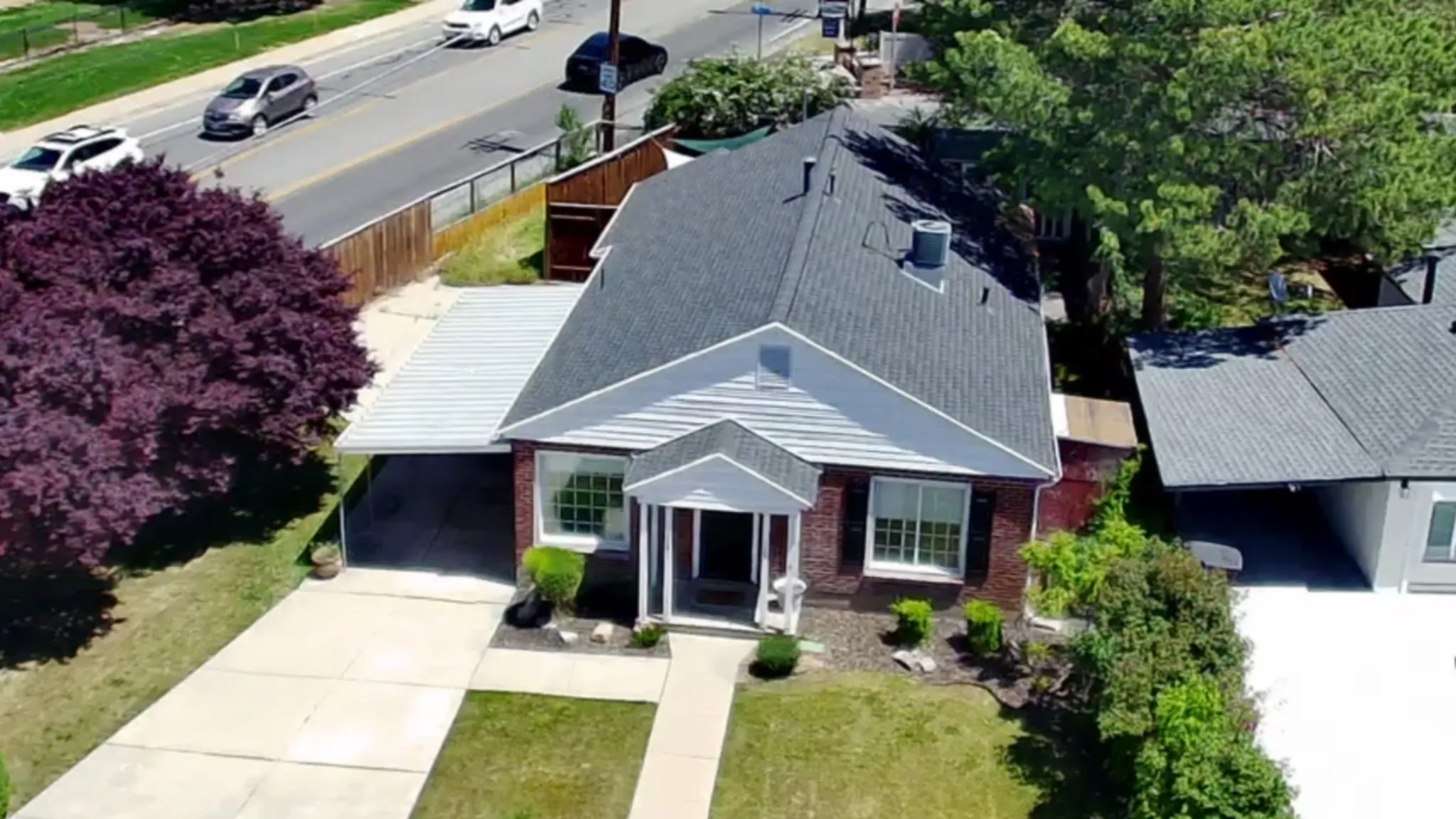 Brick exterior residence featuring a covered carport, mature landscaping, and a paved driveway