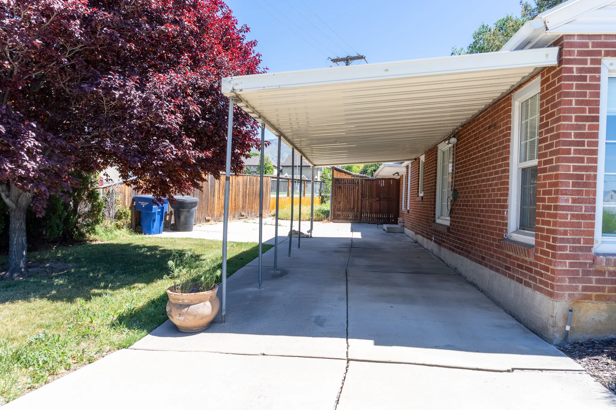 Red brick exterior with multiple windows, featuring a covered concrete driveway